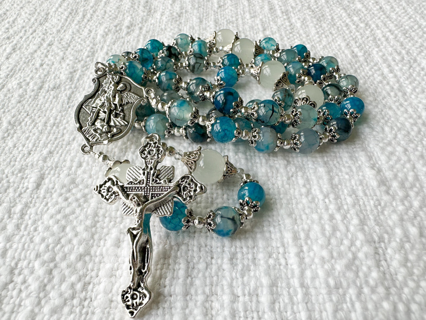 Blue and silver rosary on a white textured background