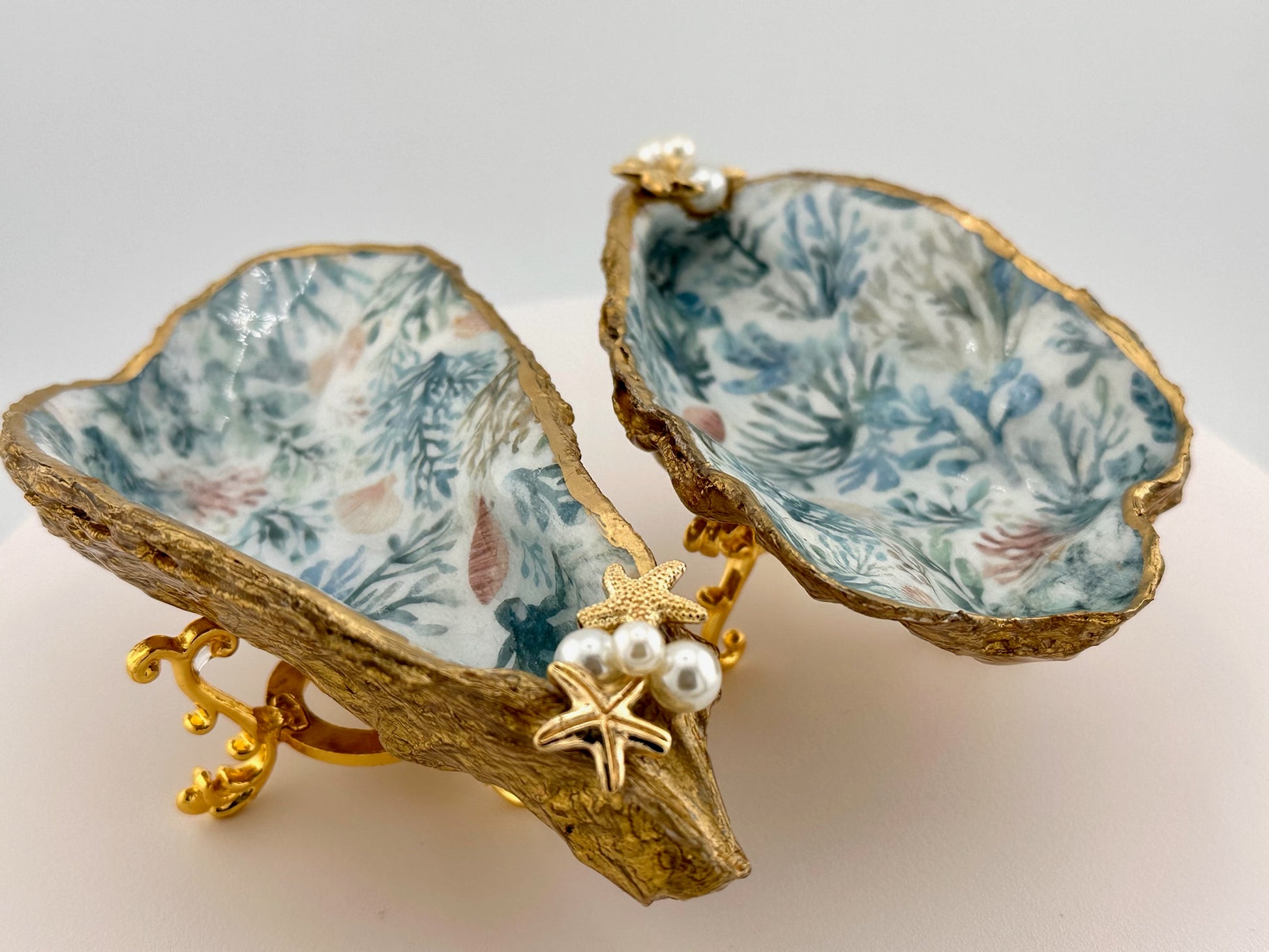 Decorative oyster shell with coral pattern and gold accents on a white background