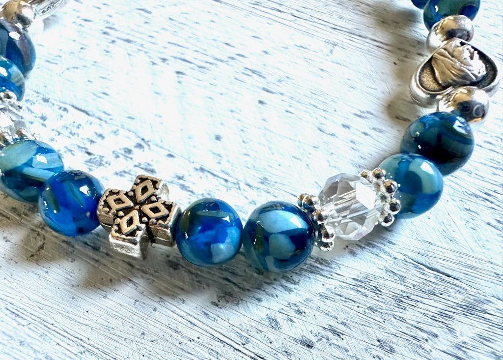 Blue beaded bracelet with decorative charms on a light wooden surface