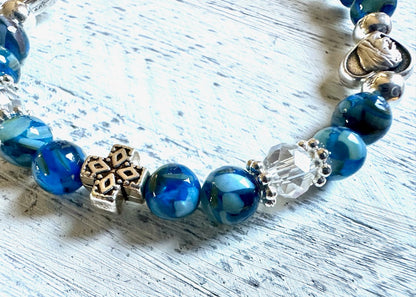 Blue beaded bracelet with decorative charms on a light wooden surface